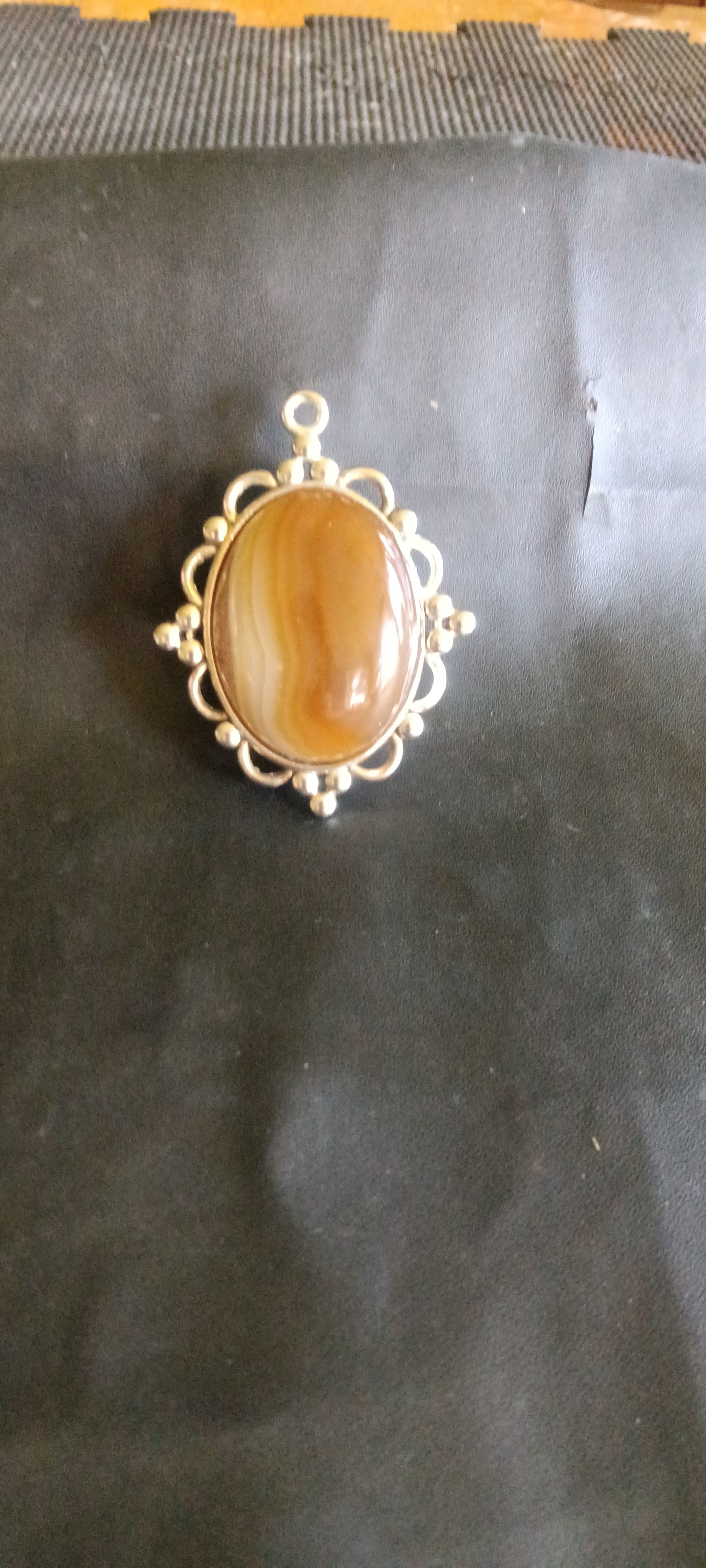 Oval, high-polish Botswana Agate gemstone pendant with caramel brown, milky white, and translucent tan bands in a silver setting, one of a kind. Rockhound Studio.