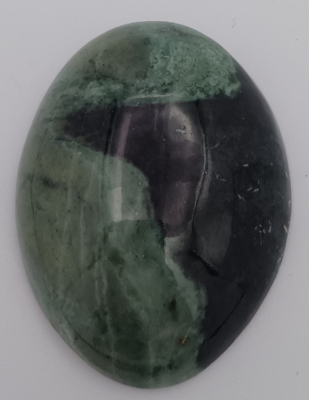 Oval-shaped gemstone with green and purple colors on a white background