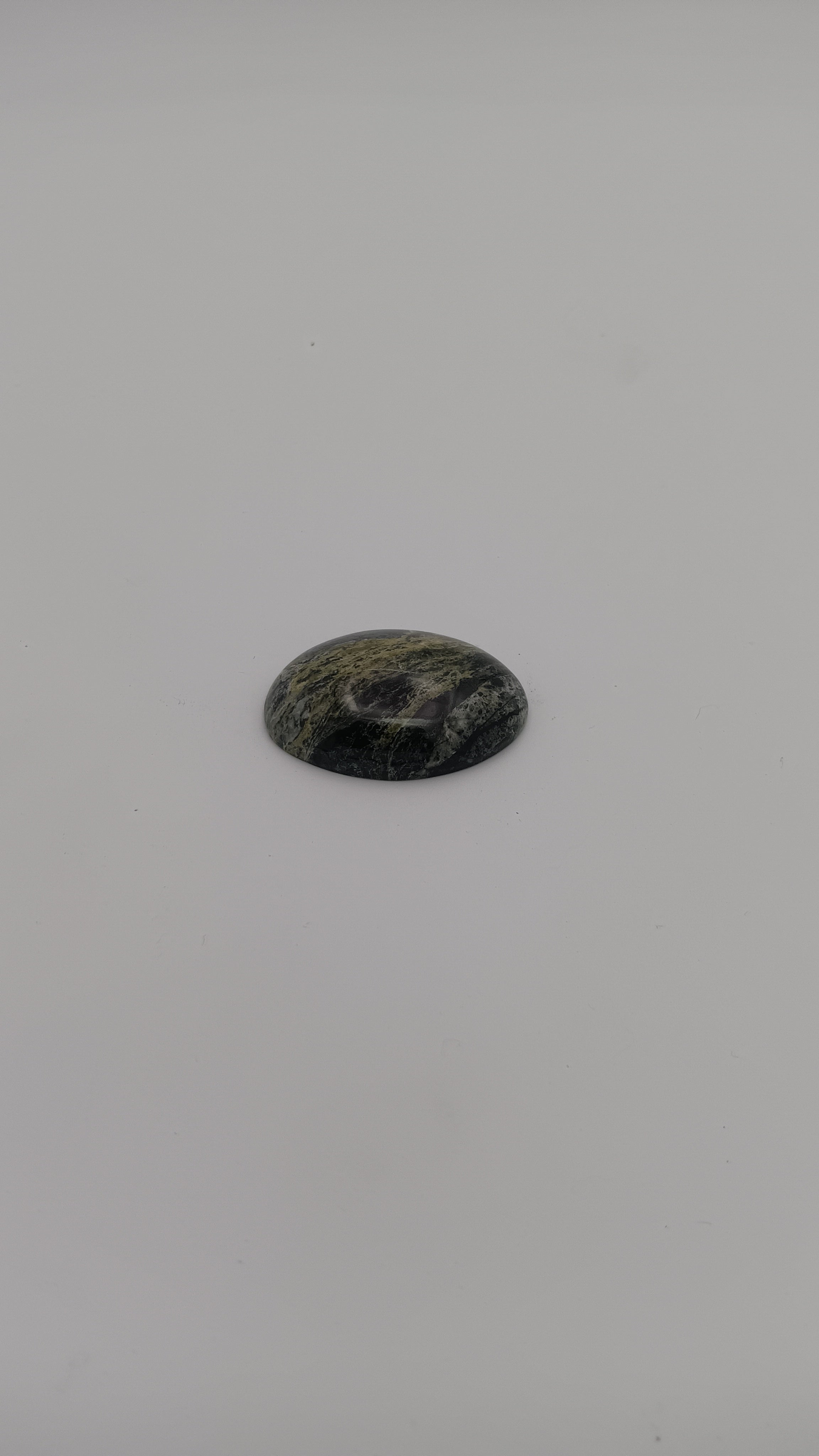 Oval stone with yellow-green, dark green, gray, and black zones, high polish, set in ornate silver filigree. Rockhound Studio.