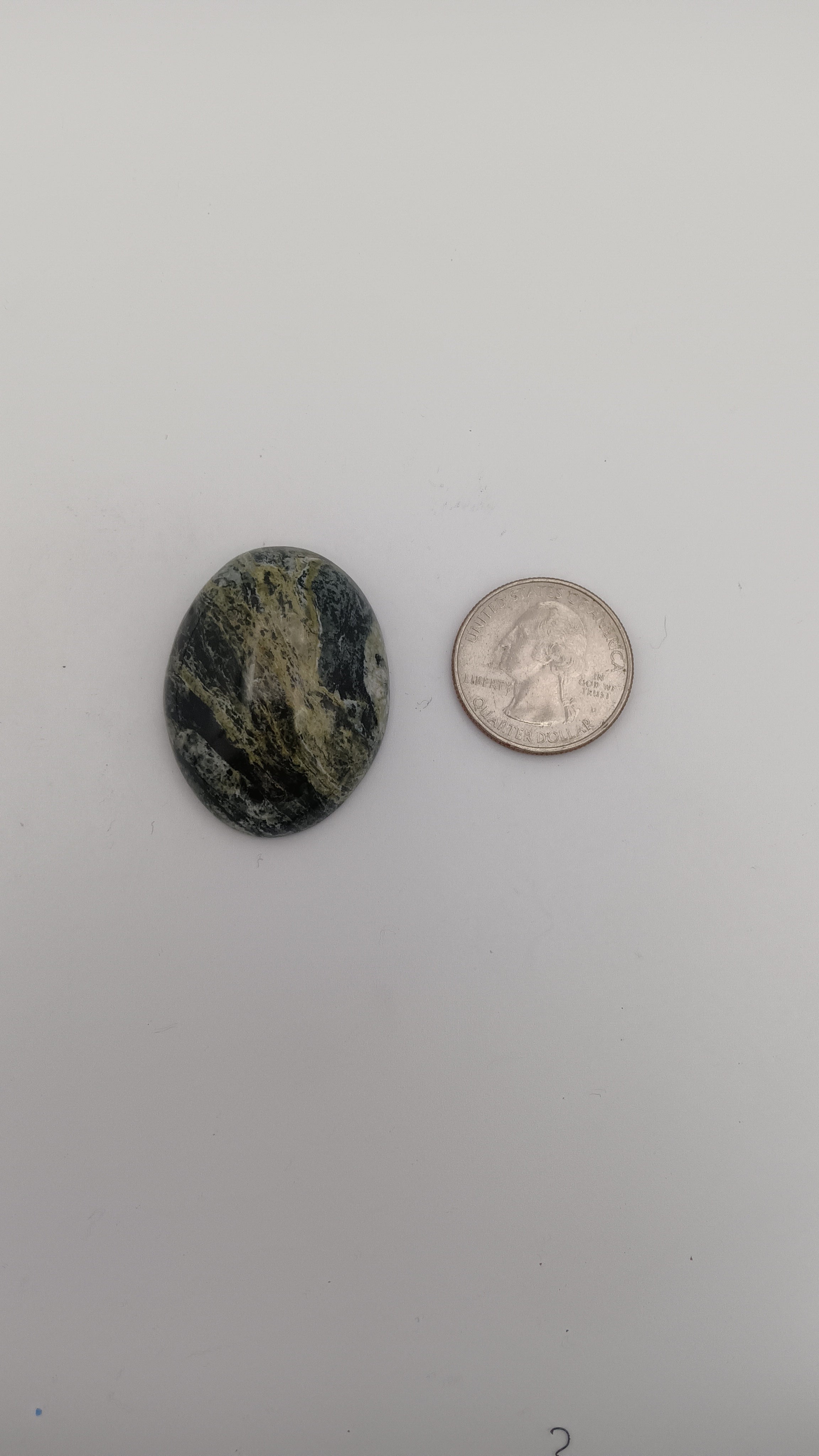 Oval stone with yellow-green, dark green, gray, and black zones, high polish, set in ornate silver filigree. Rockhound Studio.