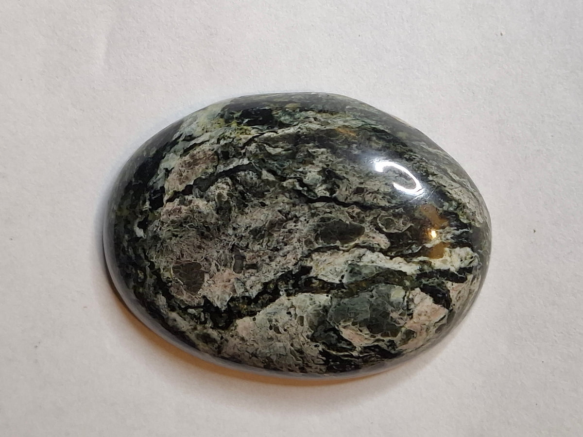 Angled view of a high-polish black and grey veined jasper cabochon, highlighting its dark and light patterns.