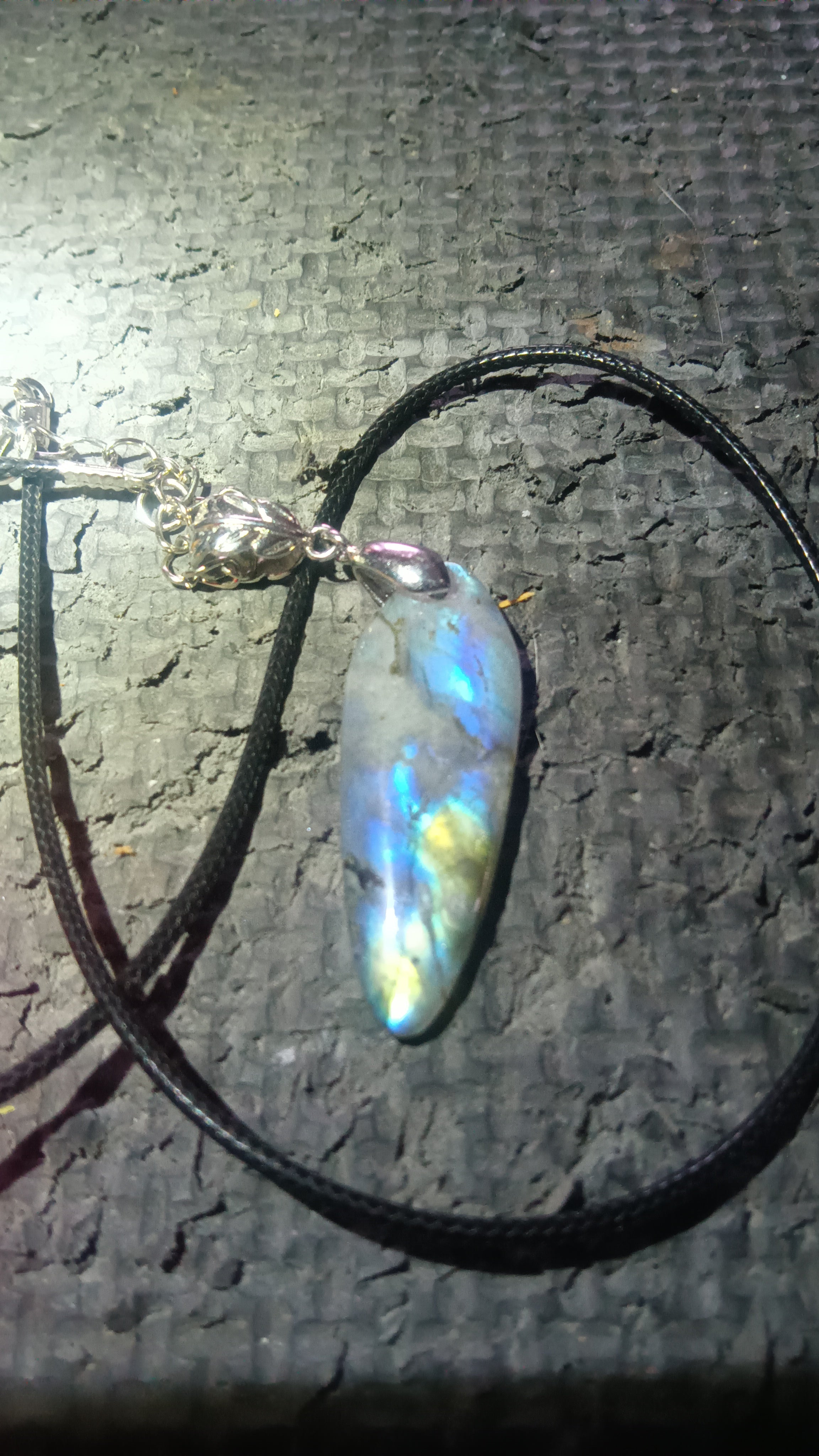 Long, narrow, surfboard-shaped labradorite cabochon with shifting blue, yellow, green flash. Handcrafted polished stone. Rockhound Studio.