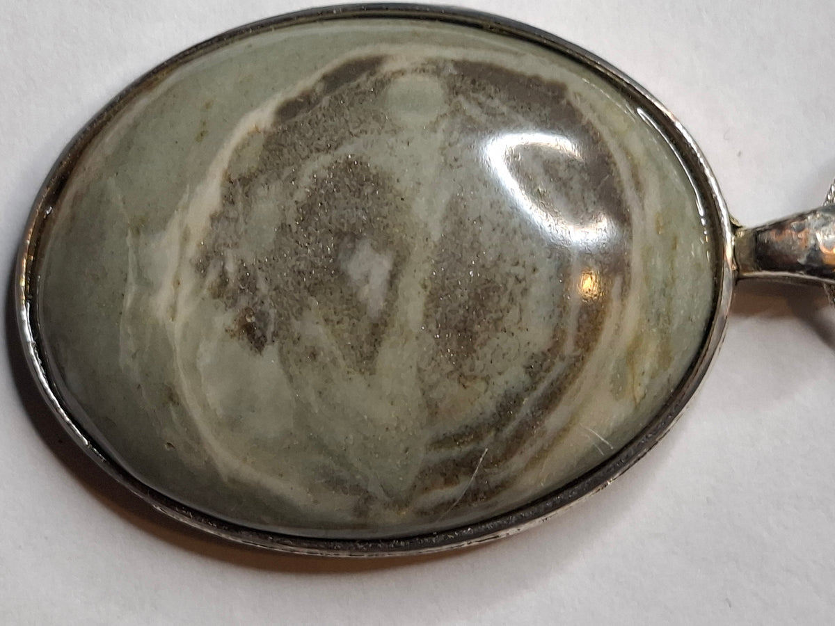 Close-up of the oval Banded Micaceous Quartzite pendant, highlighting the grey, cream, and green swirls with mica glitter.