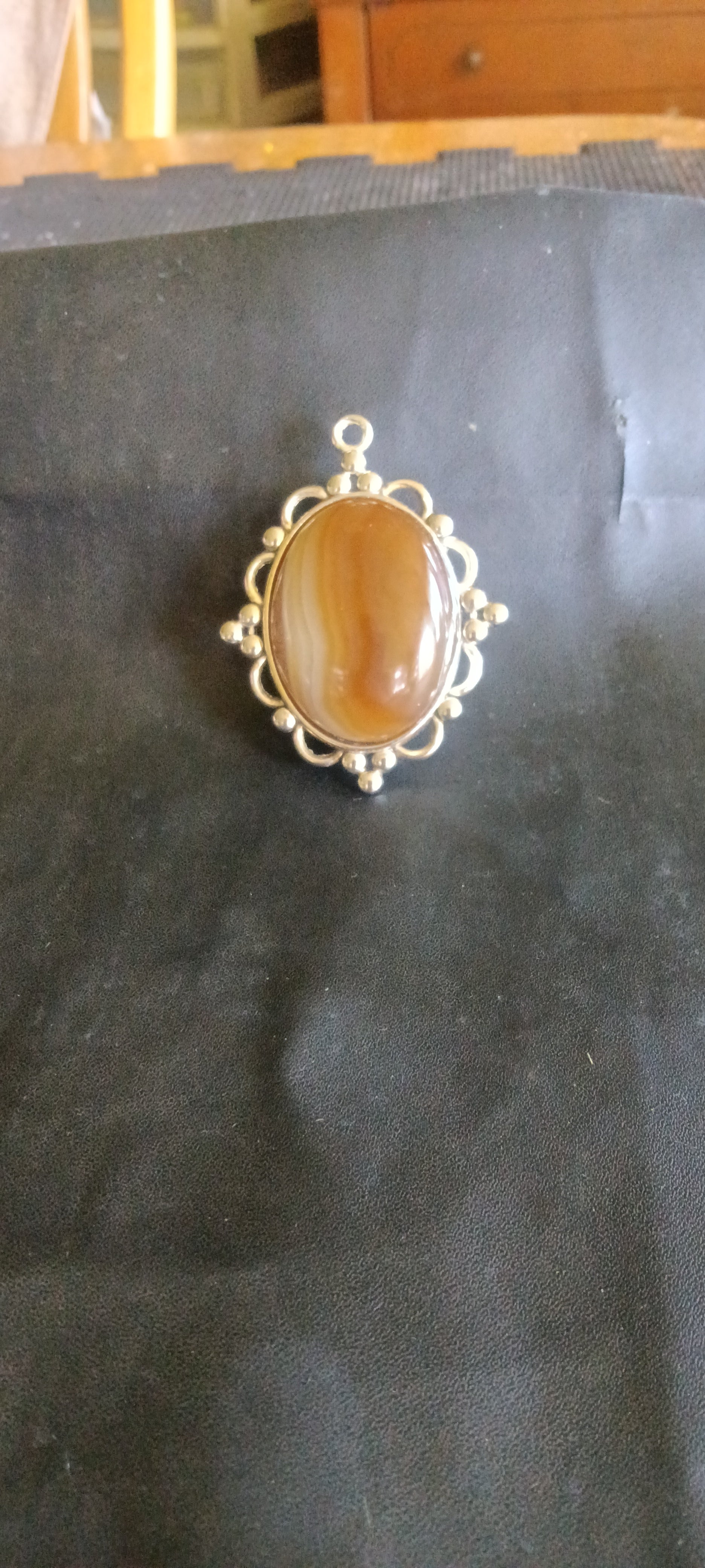 Oval, high-polish Botswana Agate gemstone pendant with caramel brown, milky white, and translucent tan bands in a silver setting, one of a kind. Rockhound Studio.